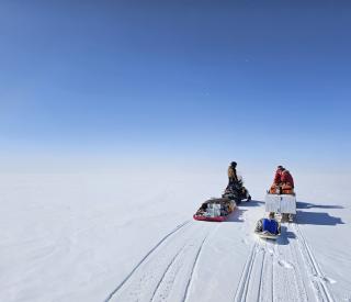 The team snowmobiling to a remote field site.